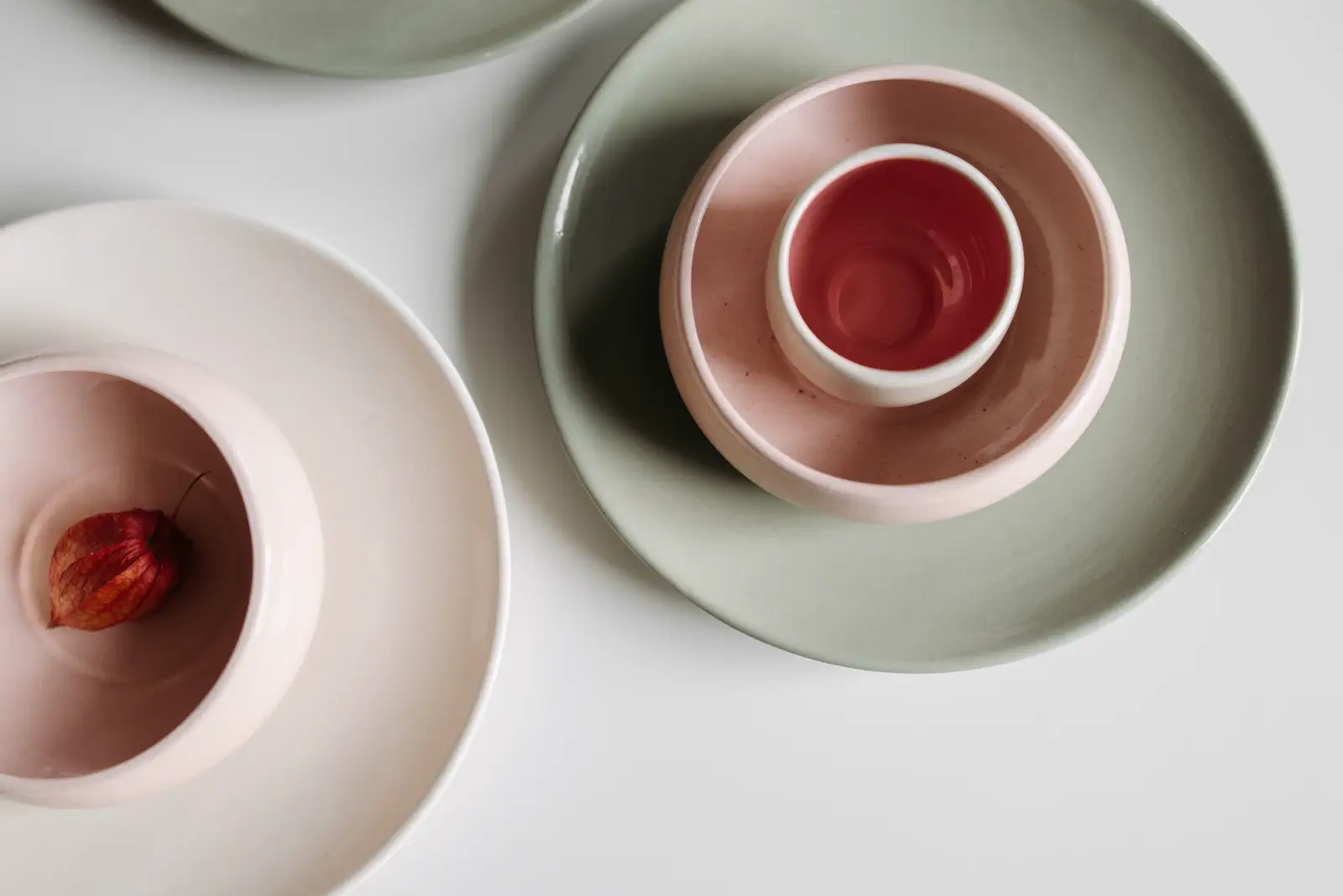 Top view of pink and sage-green plates and bowls on white.
