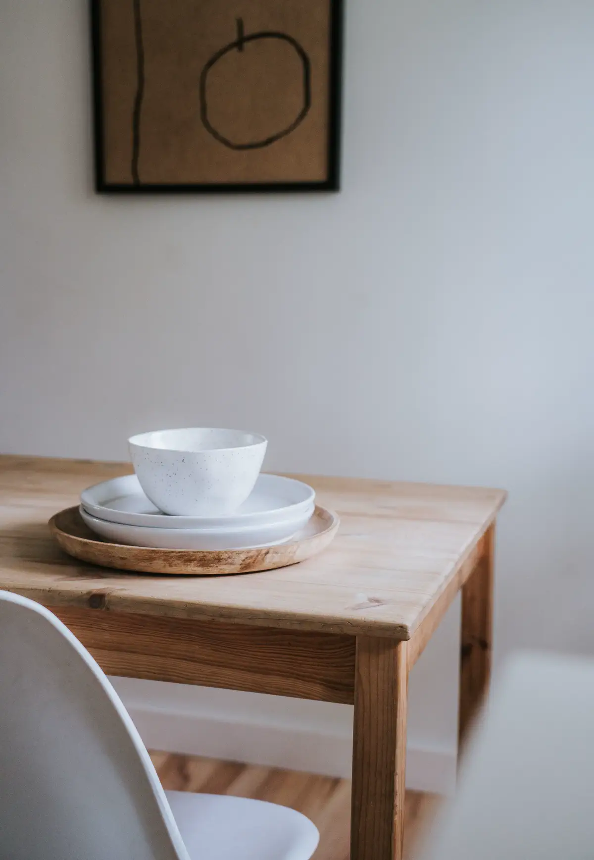 Stacked white bowls on a small wooden table, softly out of focus around them.