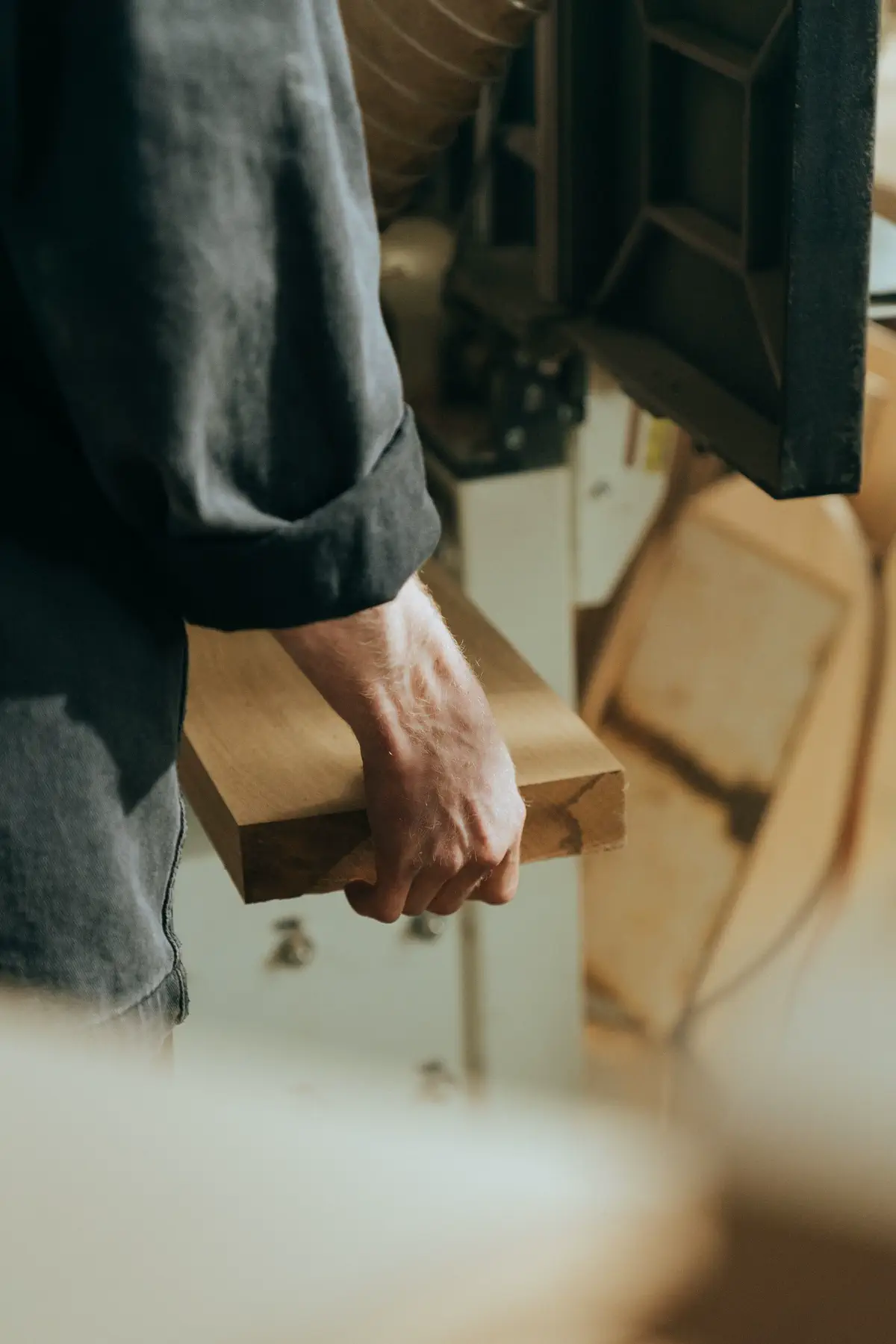 Close view of the maker's hand holding a block of timber.
