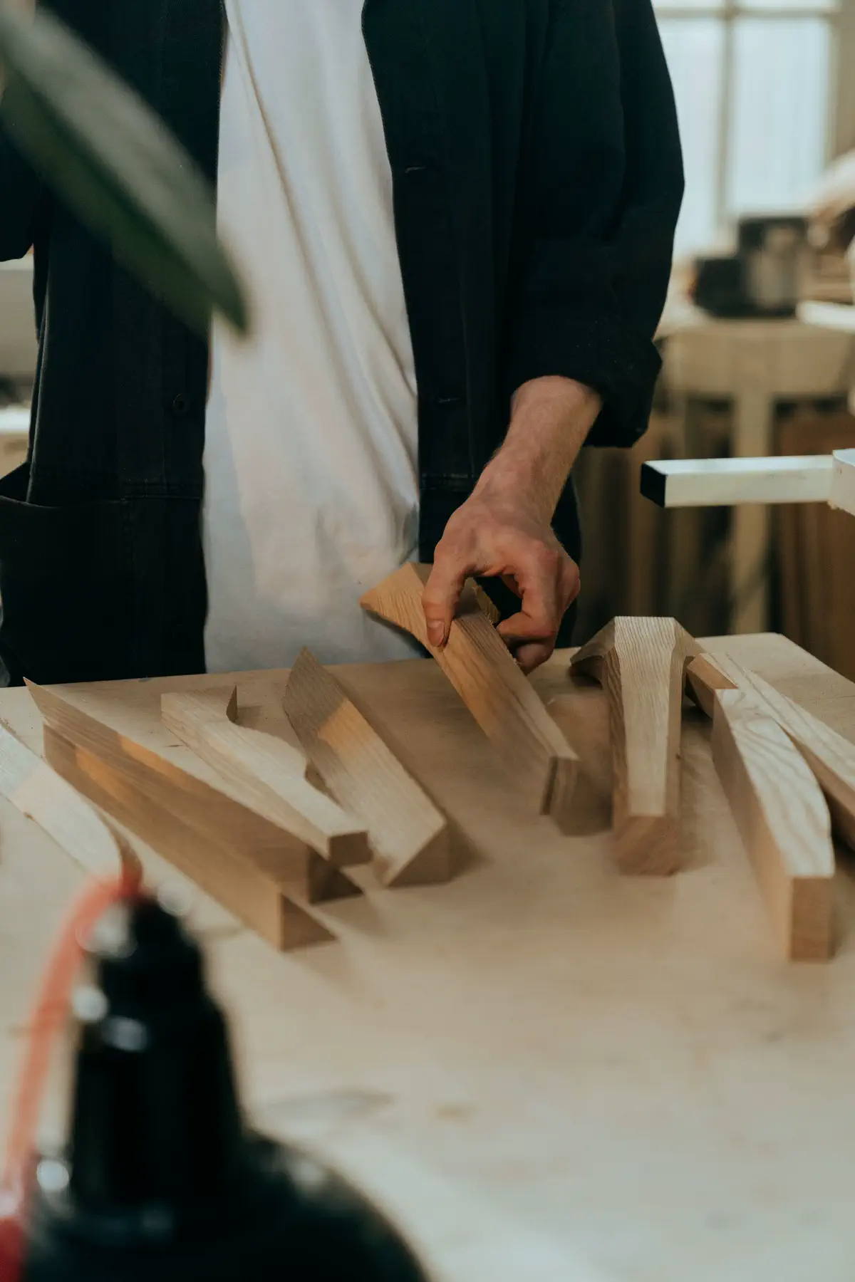 Hands sorting cut wooden parts on a pale bench.