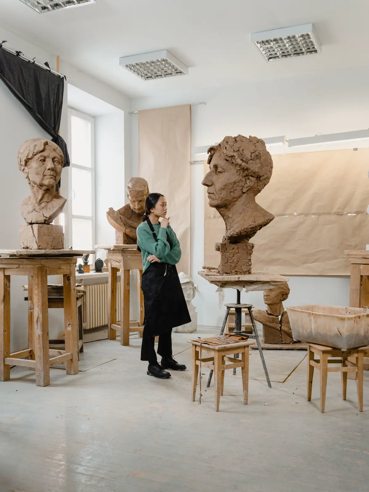 The second sculptor contemplating the busts under a high white ceiling.