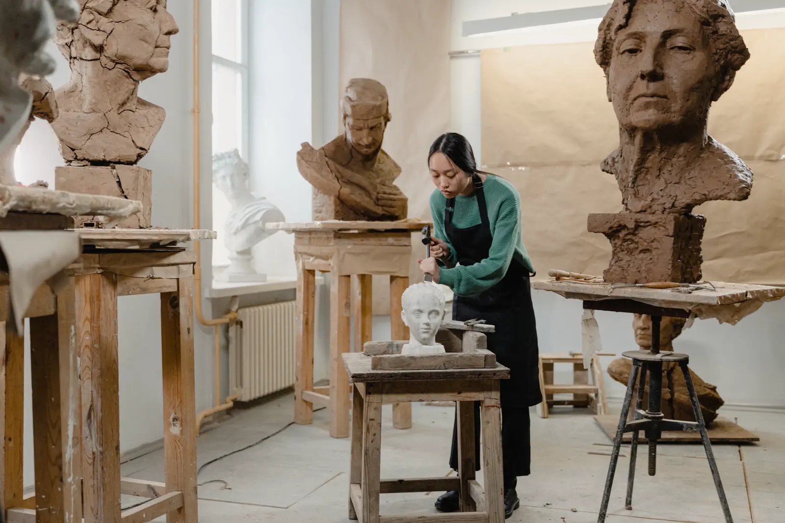 The second sculptor working on a small plaster head at a stand.
